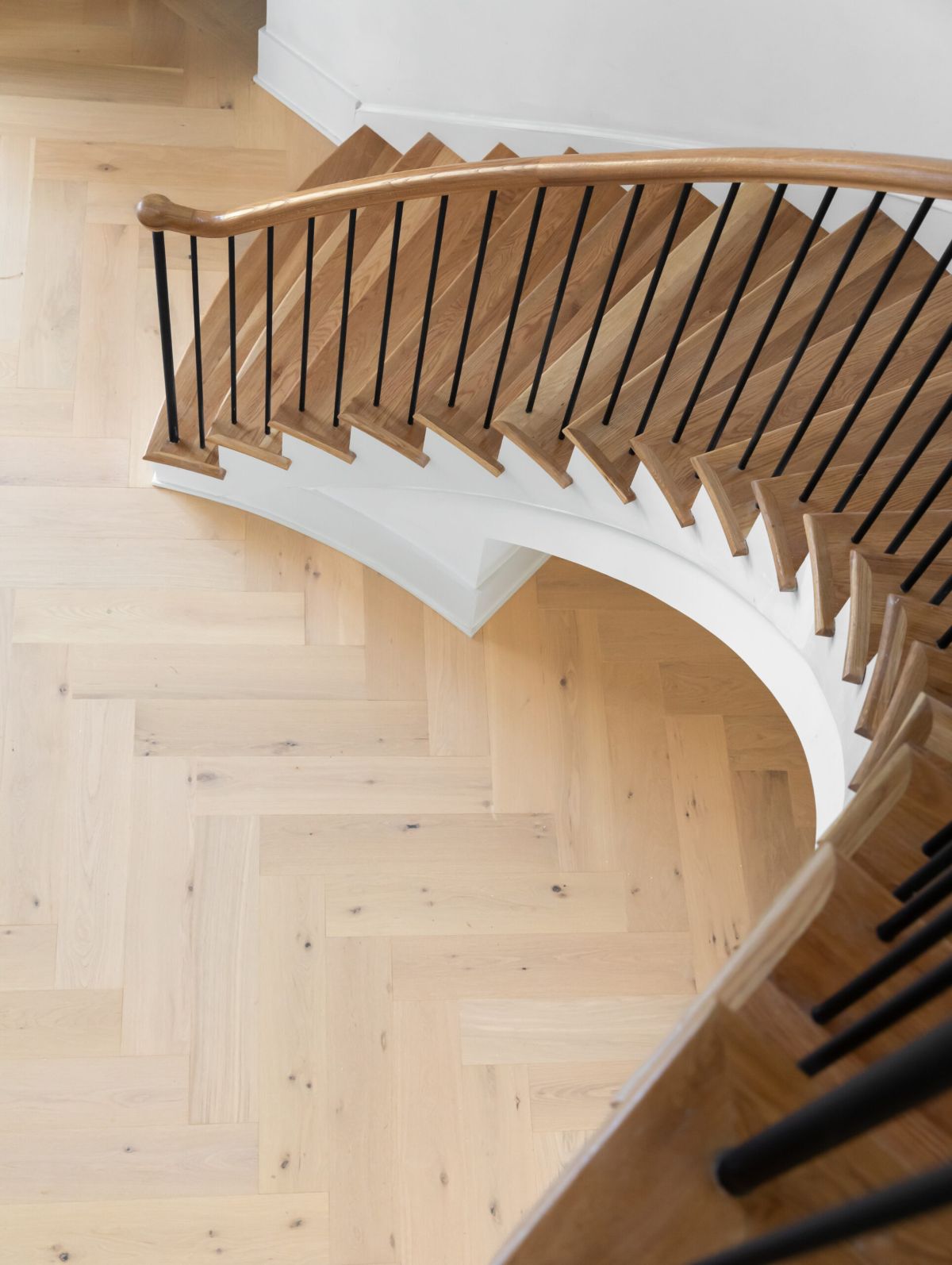 Curved staircase with herringbone wood floor